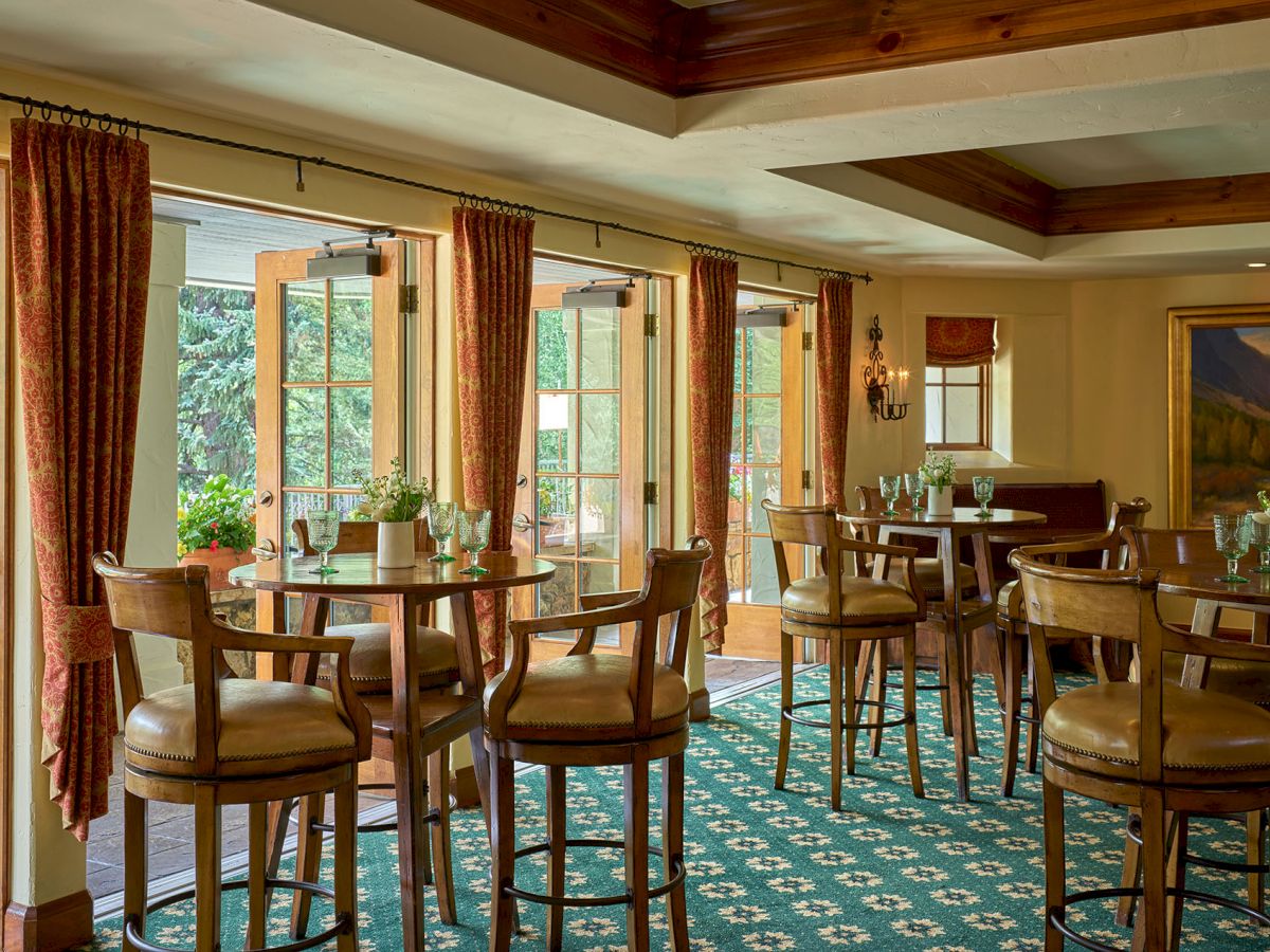 A cozy dining area with wooden chairs and tables, large windows, and warm lighting, perfect for relaxed meals and conversation.