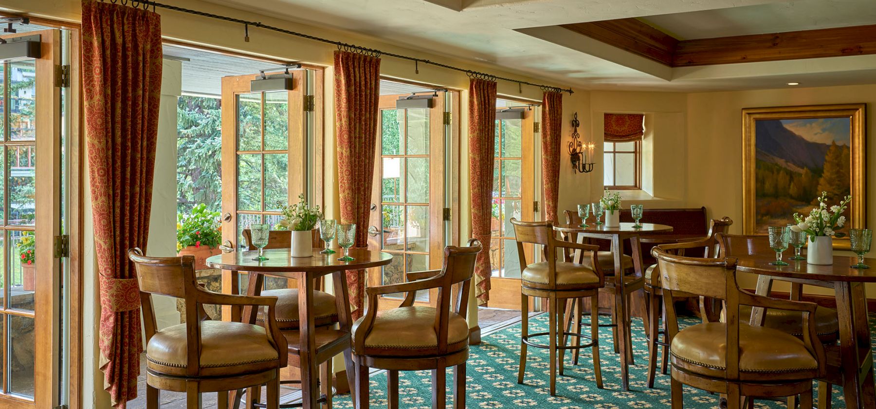A cozy dining area with wooden chairs and tables, large windows, and warm lighting, perfect for relaxed meals and conversation.